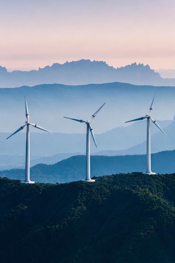 Wind turbines on a forested mountain ridge at dusk